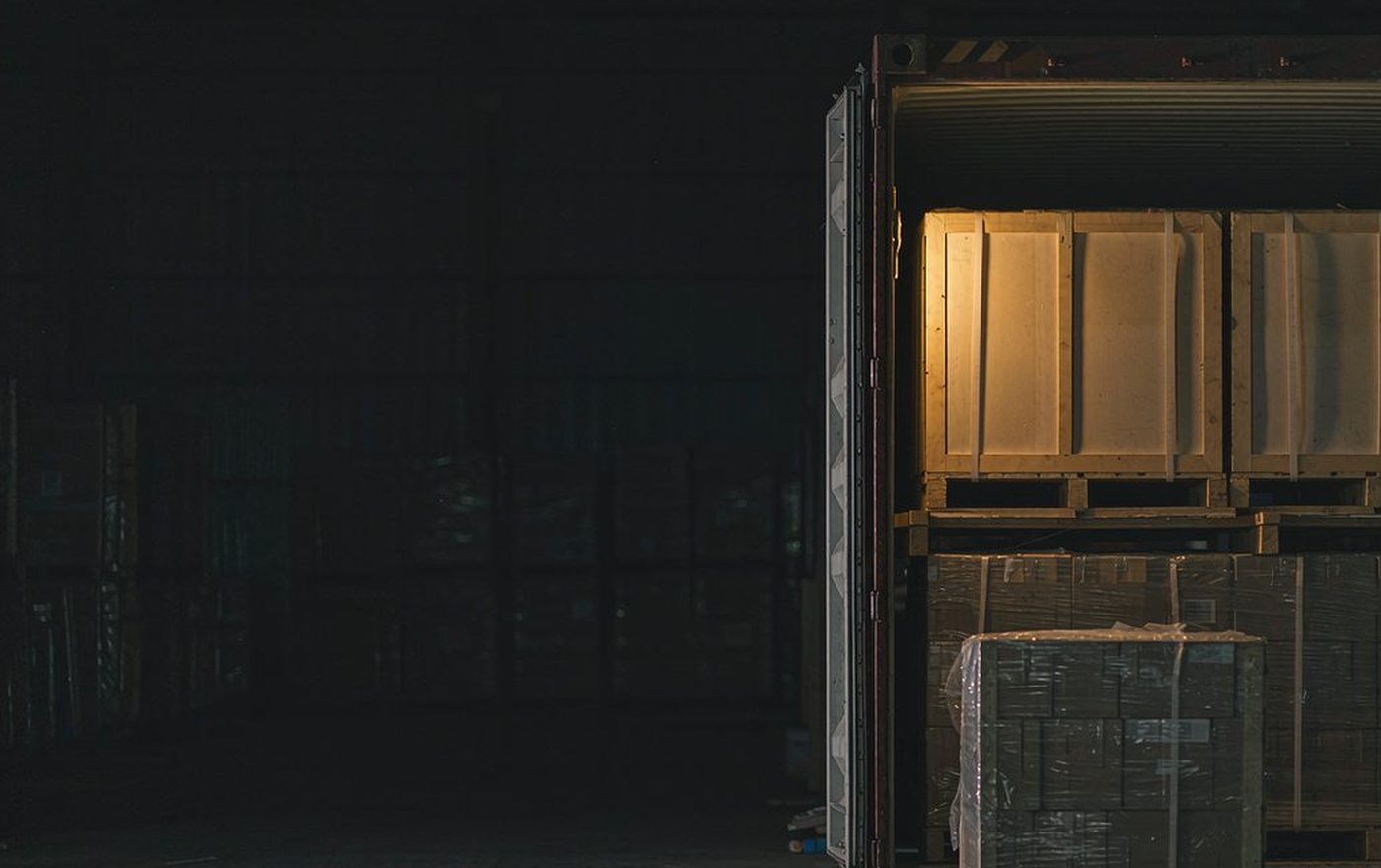 Wooden crates and cartons packed on pallets inside an open shipping container